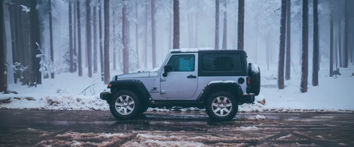 A rugged SUV parked on a snowy forest road, surrounded by a serene winter landscape.